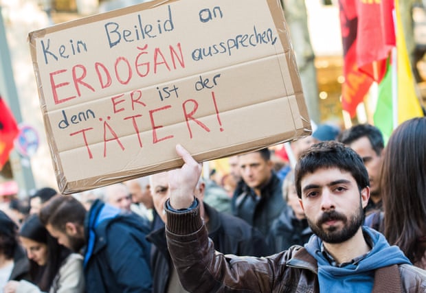 A man holds up a sign that reads ‘No offering condolences to Erdogan, since he is the perpetrator’
