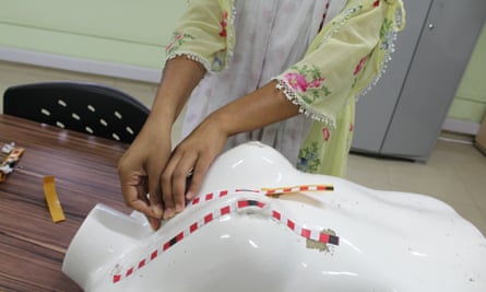 A woman feels striped tape on a dummy to practise her technique.