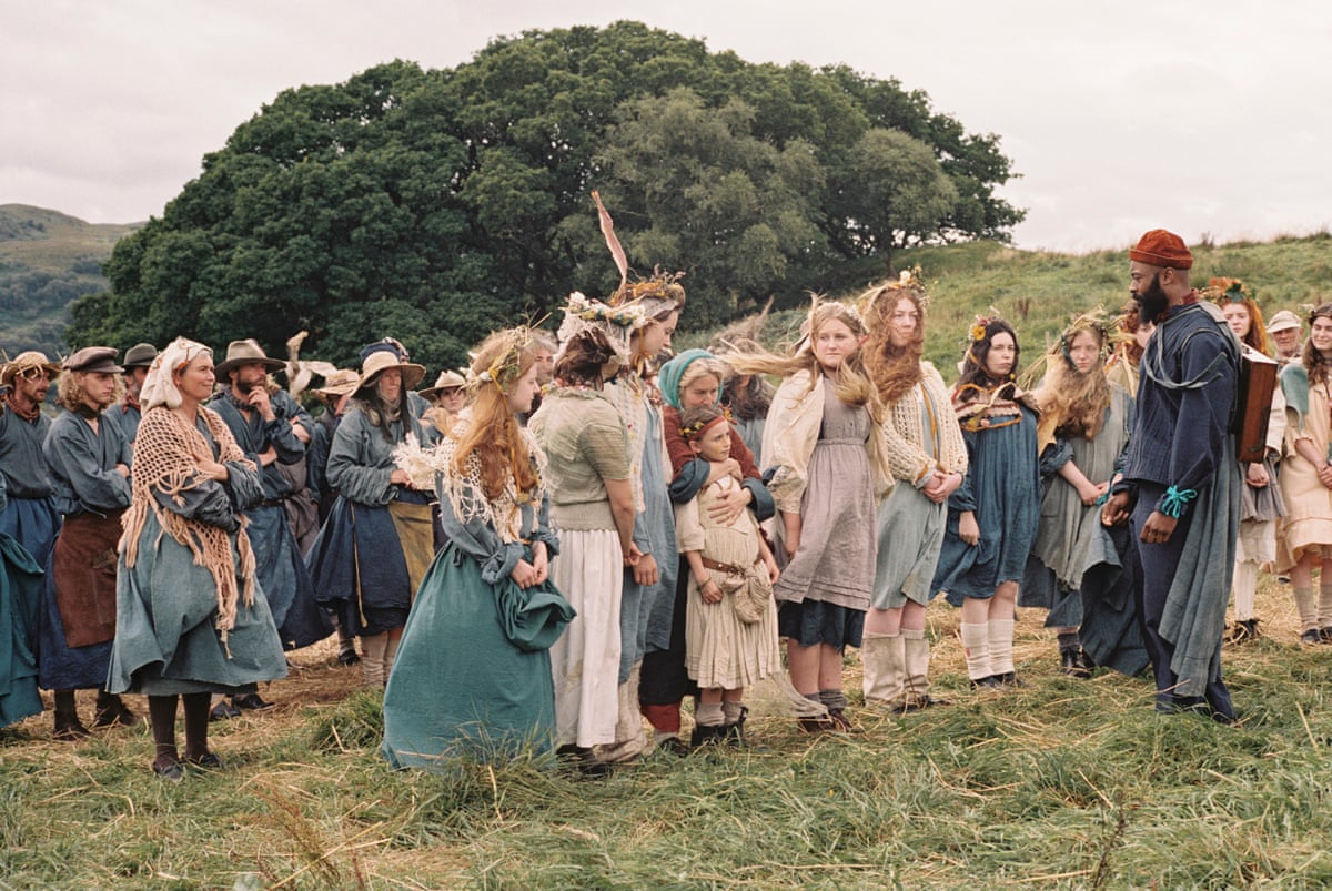 A group of agricultural workers – men, women and children – in a field, dressed in old-fashioned clothes