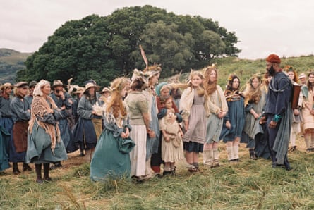 A group of agricultural workers – men, women and children – in a field, dressed in old-fashioned clothes