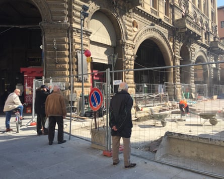 Men looking through a fence at construction work