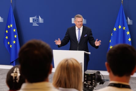 Maroš Šefčovič on a podium between two EU flags