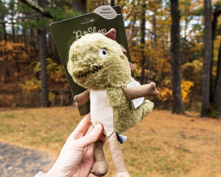 a person holding a dinosaur dog toy outside