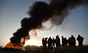 Workers on strike stand next to burning tyres as they block the access to the Total refinery of Donges, western France, to protest against the government’s planned labour law reforms.
