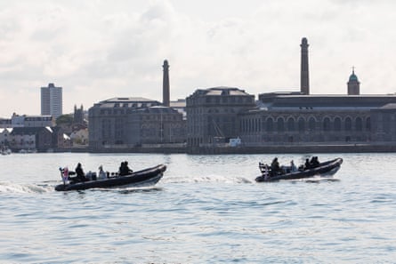 Two Royal Navy RIBs glide on Plymouth sound, with Royal William Yard in the background.