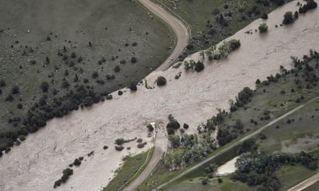 An aerial view shows a flooded river and washed-out bridge.