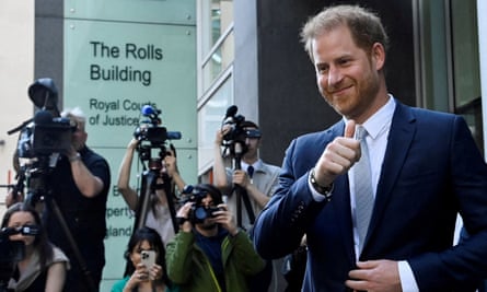 People photograph or film Prince Harry as he smiles and gives a thumbs-up