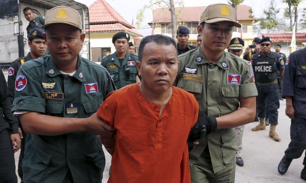 Yem Chrin is escorted by police officers into the provincial court in Battambang province, Cambodia, on Thursday.