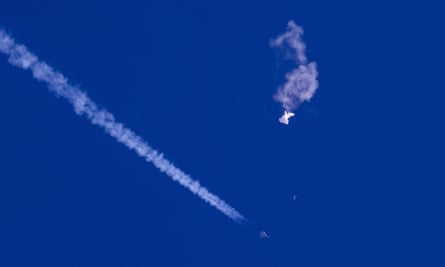 The remnants of a large balloon drift above the Atlantic Ocean, just off the coast of South Carolina, with a fighter jet and its contrail seen below it, on 4 February.