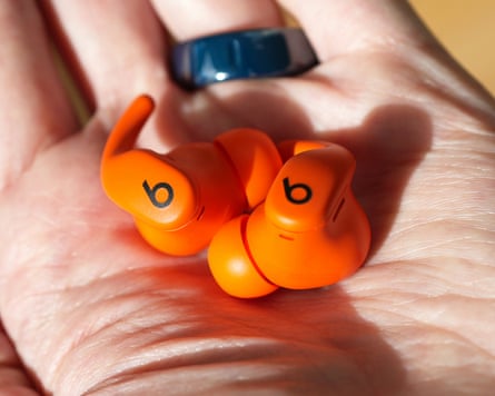The Beats Powerbeats Fit earbuds in the palm of a hand.