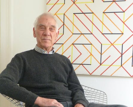 Peter Ahrends sitting in front of a geometric design on the wall