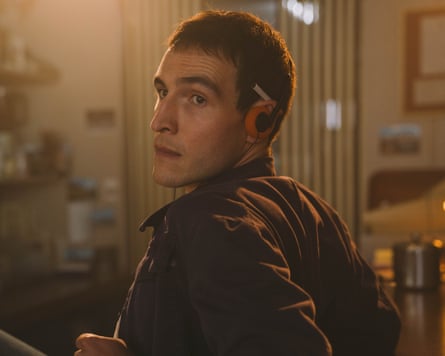man looks over his shoulder in dimly lit room