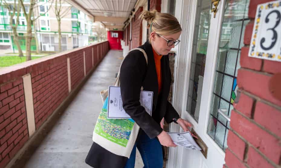 A volunteer posts leaflets for a local community support group through letterboxes on a north London housing estate. 