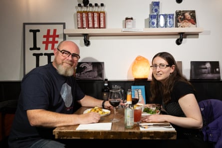 Andy and Louisa sitting at the restaurant table smiling at the camera
