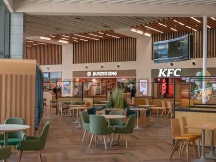 Interior of a service station, showing cafe chairs and tables, with KFC and Burger King in the background