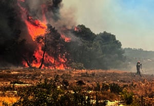 Trees burn in a forest attended by a firefighter