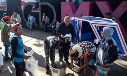 Neighbours give coffee to migrants from Central American countries heading in a caravan to the US, during a stop outside a temporary shelter in a sports centre in Mexico City.