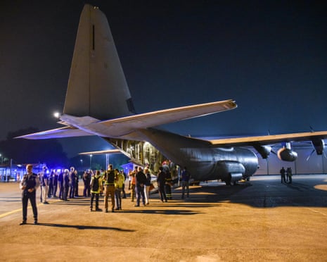 People gathered around the open rear hatch of a cargo plane