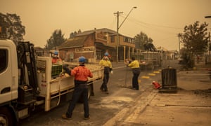 Workers erect fences in front of destroyed buildings in the main street of Cobargo, NSW.