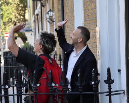 Zack Polanski and an activist stand outside a house waving to someone out of view on the other side of the street while doorknocking