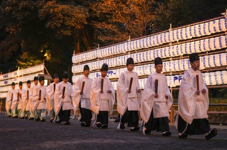 Shinto priests walk past paper lanterns at the Meiji Shrine in Tokyo.