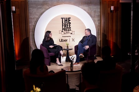 A man and a woman sit across from each other at a live speaking event