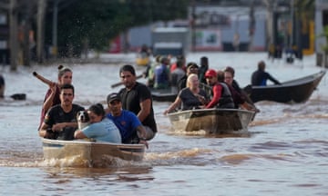 People on boats move through floodwater on a flooded street in Porto Alegre