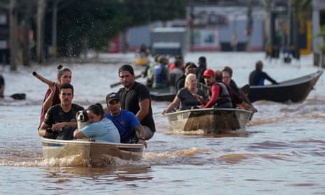 People on boats move through floodwater on a flooded street in Porto Alegre
