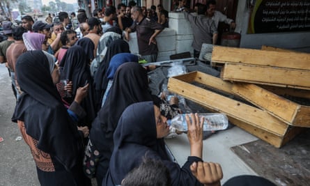 Palestinians wait in front of a bakery shop in Rafah, Gaza on Sunday