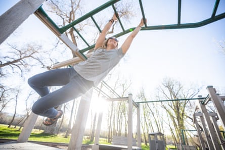 Woman playing on monkey bars in a playground.