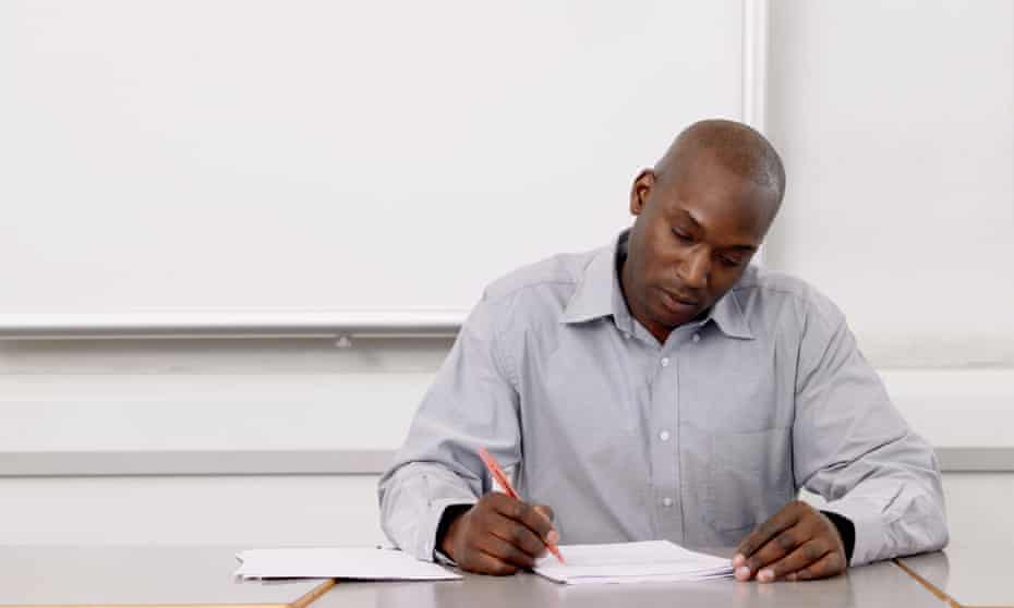 A black male teacher marks essays