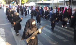 In the parade young girls wore niqab-style black veils and carried cardboard cutouts of guns