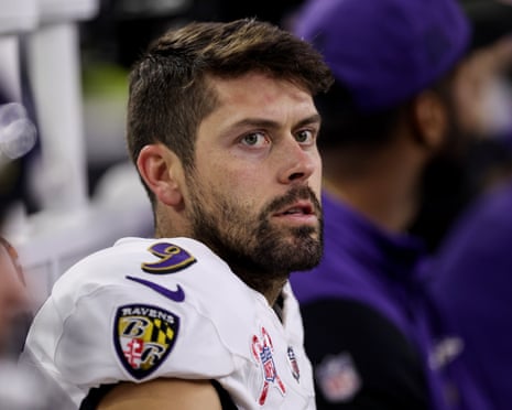 Justin Tucker, bearded, in a white Ravens jersey, looks over his shoulder with concern