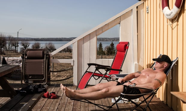 An inmate at Bastøy prison in Norway sunbaths in front of a wooden cottage where he lives in the prison grounds.