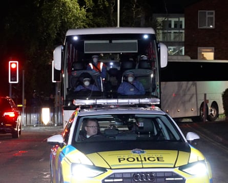 A police car escorts a coach with passengers wearing personal protective equipment
