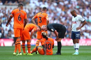 The referee Mike Dean speaks to a wounded Saint-Maximin before he is replaced.