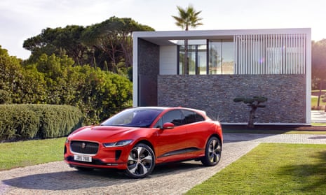 Red Jaguar iPace parked in front of a small shed