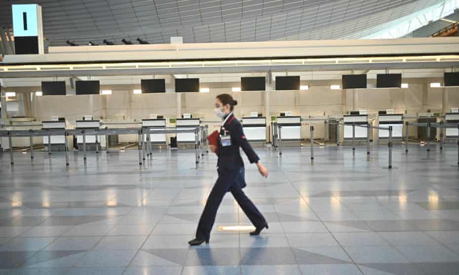 An airline employee in a face mask walks in front of closed airline counters at Tokyo’s Haneda airport in Japan.