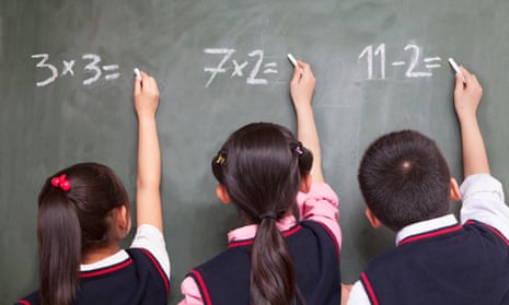 Three school children doing math equations on the blackboard