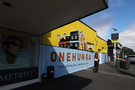 A person stands near a billboard for Onehunga