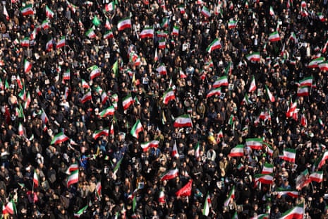 An aerial shot on a huge mass of people, some of whom are holding red, white and green Iranian flags.