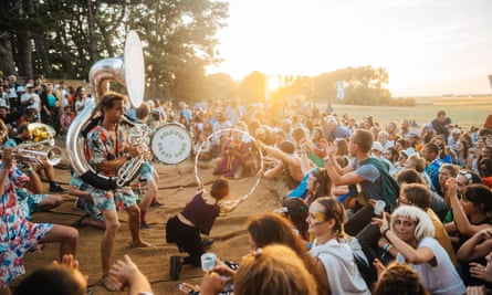 Festivalgoers surround man playing brass instrument and woman with hoop, at Pete the Monkey festival.