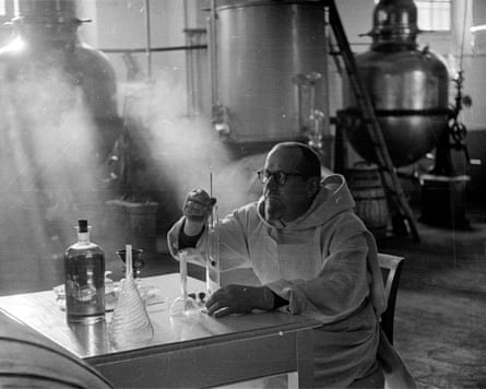 A black and white picture of a monk sitting at table with bottles and jars