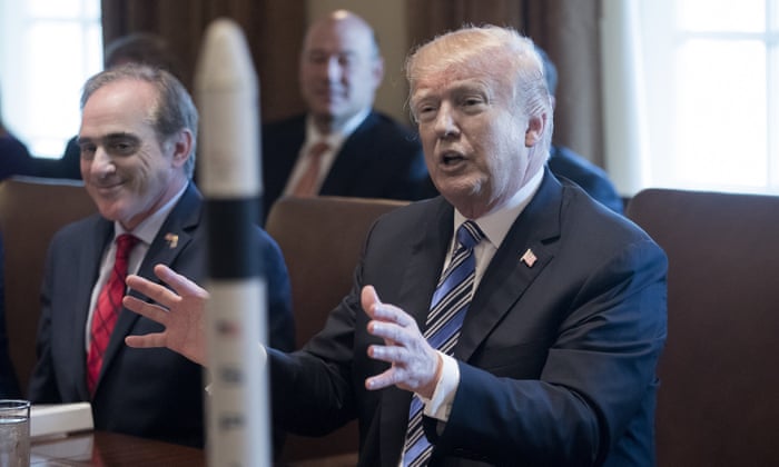 Trump gestures behind a model of a rocket. US Secretary of Veterans Affairs David Shulkin sits to his left.