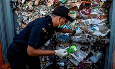 An Indonesian customs officer inspects a container filled with garbage originating from Australia, which should have contained only waste paper, but authorities also found hazardous material