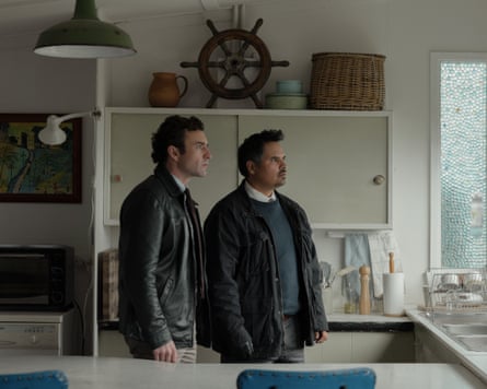 Johnny Carr and Michael Peña standing in kitchen looking out the window with shocked expressions