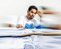 Artist Luis Manuel Otero Alcántara rests his hand on his head amid his blue-inked drawings