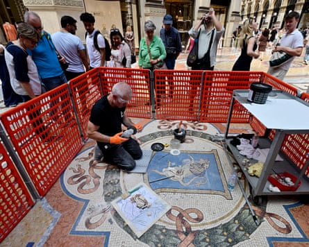 A restorer working on a mosaic surrounded by a small group of onlookers.