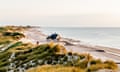 View of dunes and ocean and a typical Danish house on the beach near Skagen on the coast of North Jutland, Denmark at sunset on a summer evening.