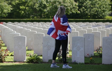 A visitor draped in a union flag walks among the headstones at the Bayeux cemetery.